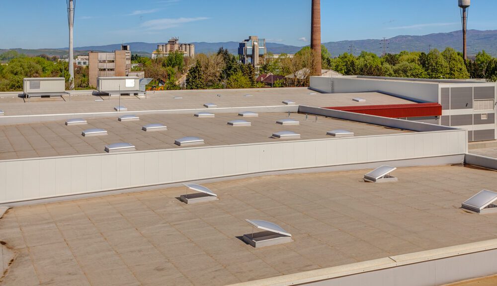 A manufacturing facility with a commercial flat roofing system and exhausts.