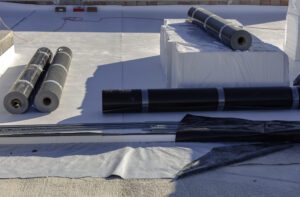 Rolls of PVC roofing materials sit on the roof to be installed.
