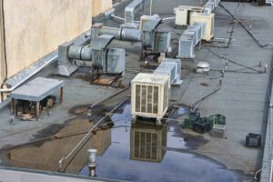 A commercial roof with air conditioning units and ponding water.