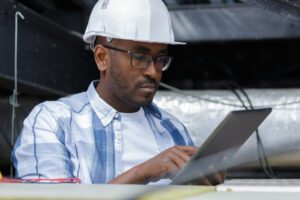 A roofing contractor documents roof repairs on a tablet.