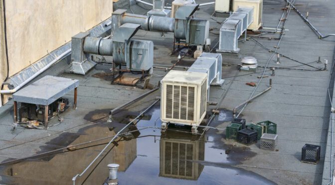 Ponding water on a flat commercial roof shows clear signs that flat roofing repair is required.