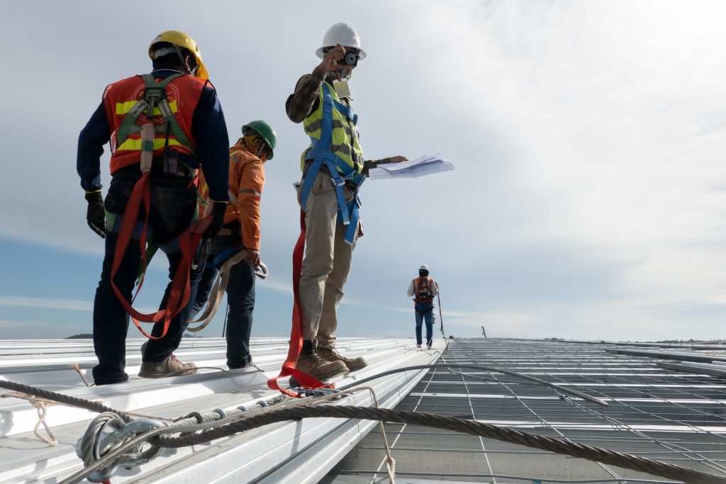 A roof inspector and his coworkers take photos of a commercial roof