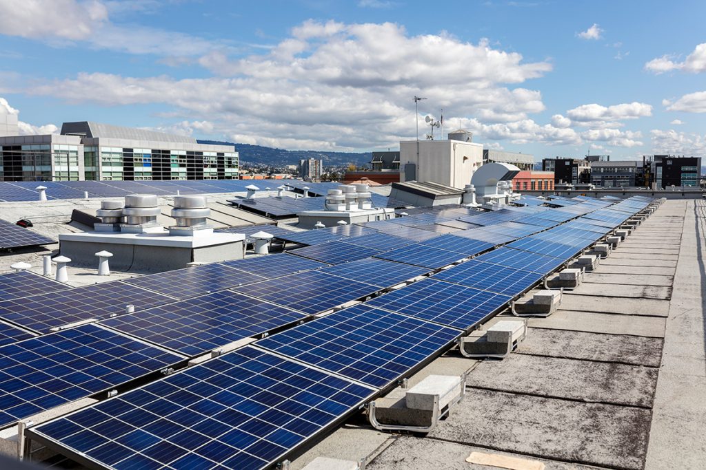 A flat roof that has multiple rows of solar panels installed on top of it