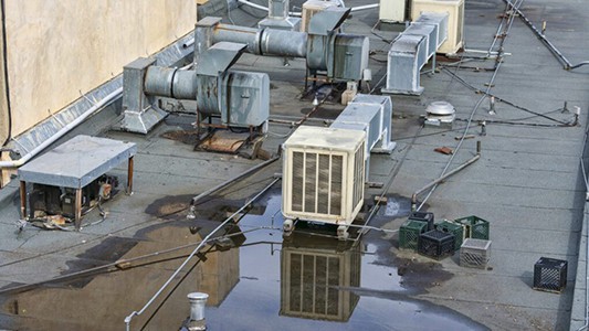 Ponding water on a flat commercial roof shows obvious signs that flat roofing repair is required.