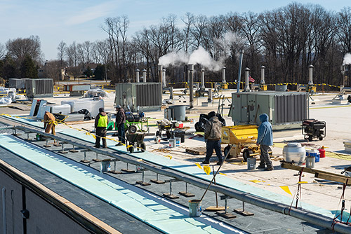 Workers from Heidler Roofing work on Dawn Foods's roof.