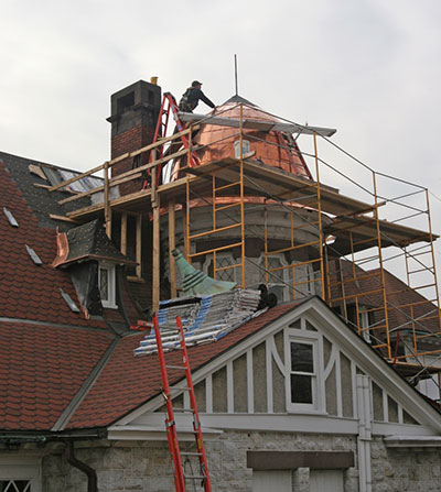A roofing technician repairing a copper dome on a building.