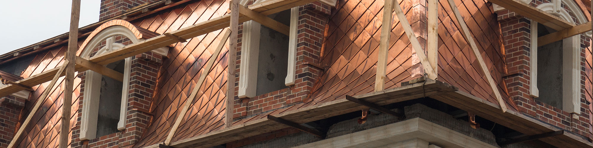 The copper roof of a building with wood support planks around it.