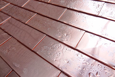 Copper roof shingles with rain on them.