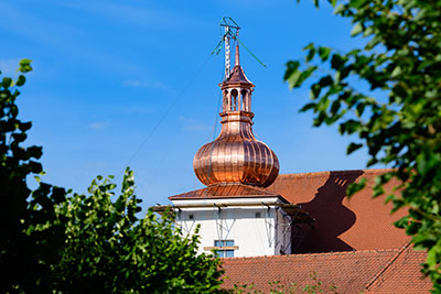A copper tower on top of a building against a blue sky.