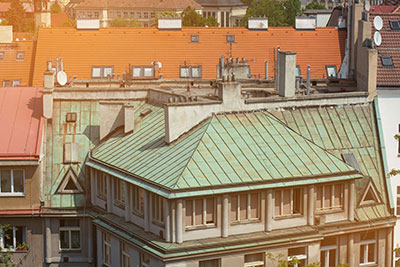 A copper roof that has aged to a green patina on an older building in the city.