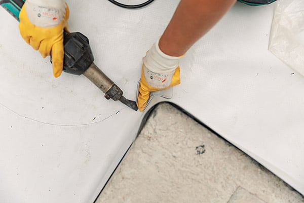 A person is fixing a corner on a PVC roof.