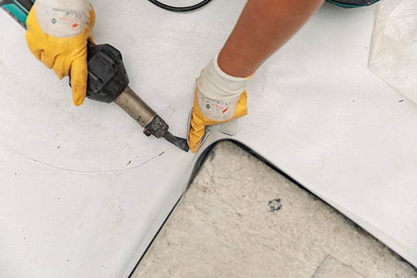 A person is fixing a corner on a PVC roof.