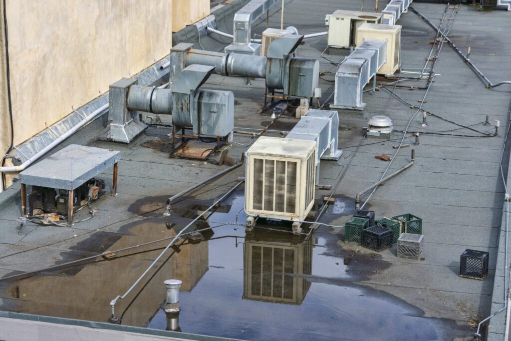 Ponding water on a flat commercial roof shows clear signs that flat roofing repair is required.