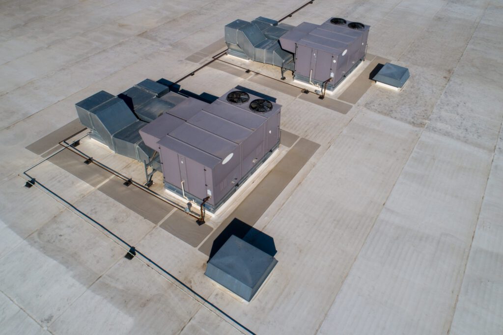 Two large HVAC units set onto a wide open commercial roof