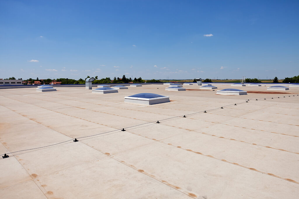 A low-angle view of a flat roof with multiple skylights